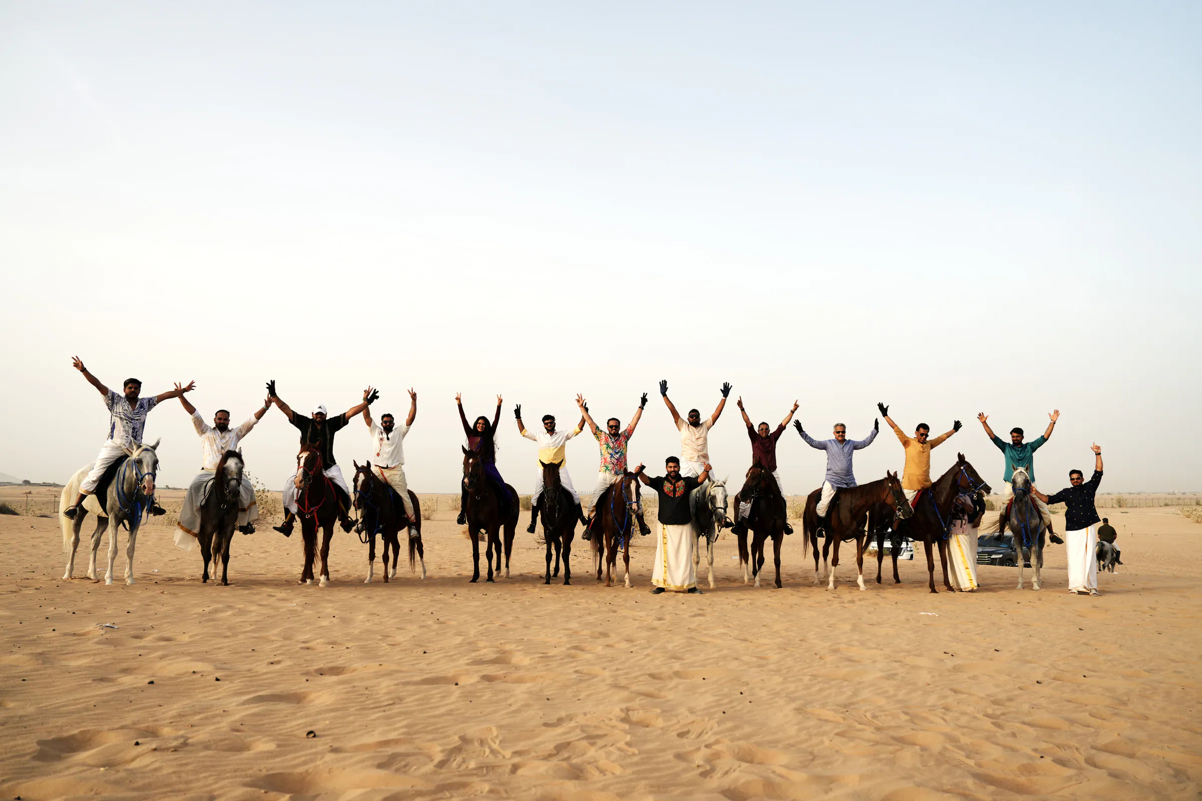 Riders on horseback raising their arms in celebration in the desert