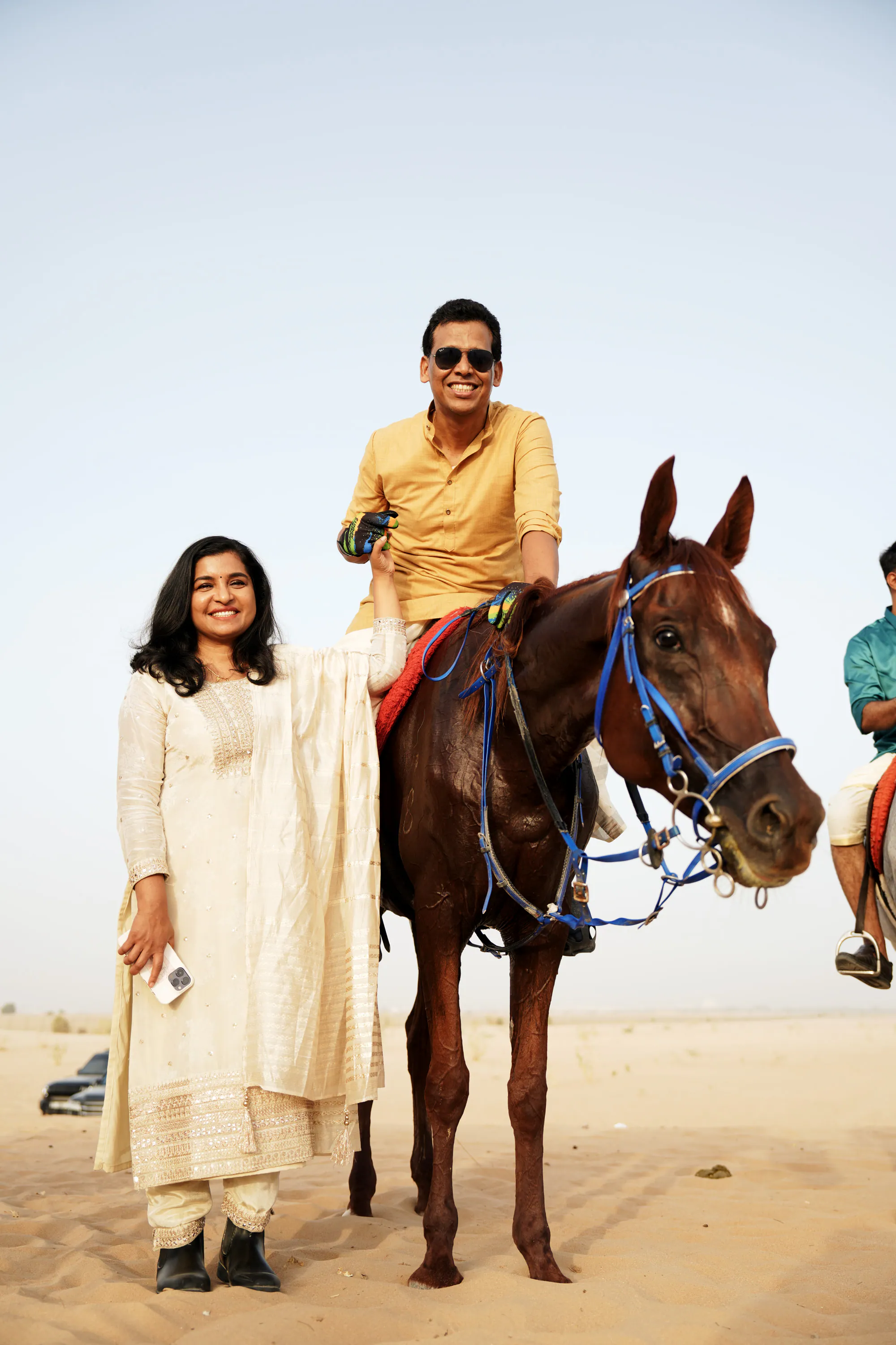 A rider on a chestnut horse with a woman in a cream salwar standing beside him